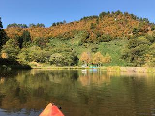 カヌーに乗り湖面から見上げる山形県飯豊町中津川地区の紅葉