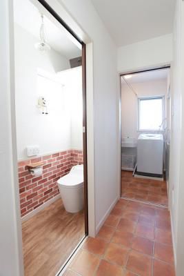 脱衣室へと続く廊下をタイル調に、トイレの壁を一部レンガ調のおしゃれな空間に
