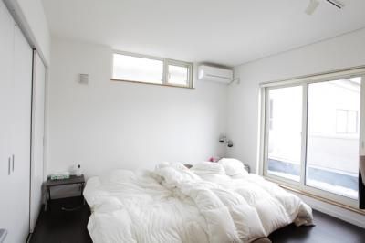 色の濃い床材と白の内装材でメリハリのあるモダンな寝室
