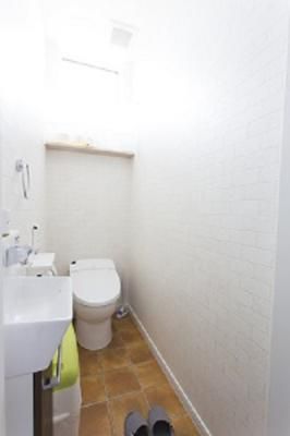 テラコッタタイル調の床とレンガクロスのトイレ