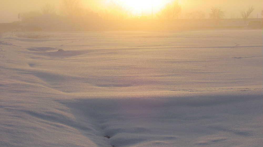 早春を思わせるような神々しい朝日を見ることができました 午前6時45分東の空から太陽が昇り始めました 気温も低く霧が立ち込めていて遠くの山並みがうっすらと見え道路の桜並木もかすかに見える幻想的な朝の風景となりました まだ雪が解けない田んぼもオレンジ色に染まっています カメラではその美しさをとらえきれませんが春を感じてほしい