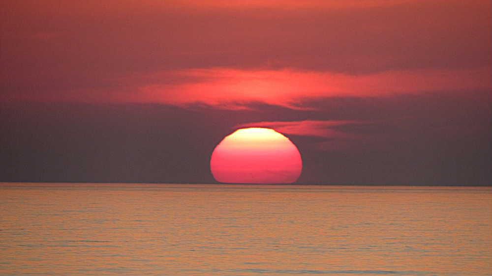 先日今まで撮ったことがないような夕日が見れました　日本海に沈む夕日でかすかに見える波間の水色とオレンジの縞模様も初めて見る風景です　秋は空が真っ赤に燃えたように夕焼けをよく見ることができますが初夏にもこんな夕日が見れるんですね