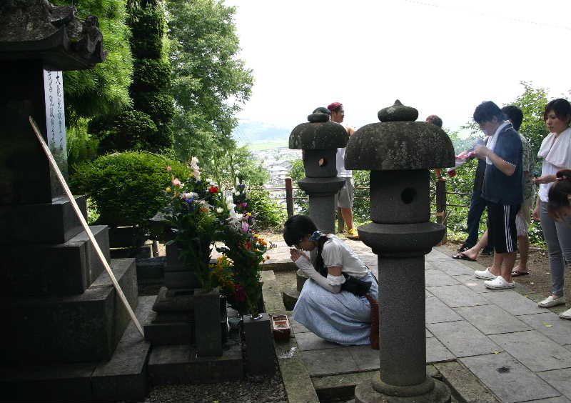 墓前に若者グループが活動報告