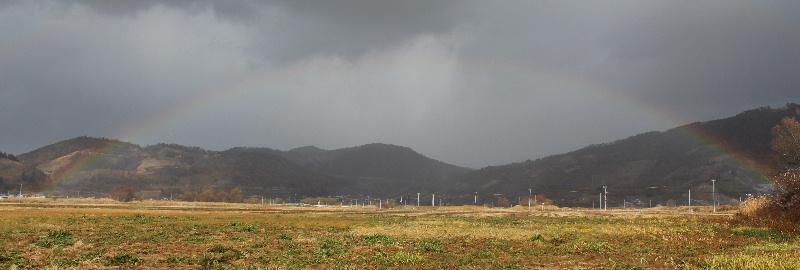 北の山すそにうっすらと虹がかかりました　端から端まで虹を初めて写真に撮りました　冷たい風が吹き 晴れたり雨が降ったりと目まぐるしく天候が変わります　初冬の風景です