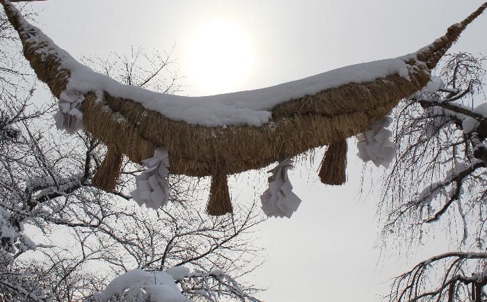 「赤湯冬点描３」烏帽子山八幡宮の参道に立つ継ぎ目なしの石の大鳥居は日本一といわれています　その大鳥居に下がる注連縄も大きく　春祭りには恒例の注連縄飾りが行われ　新聞やテレビで毎年のように報道される伝統の行事です　雪を頭に乗せ重そうにさがっています