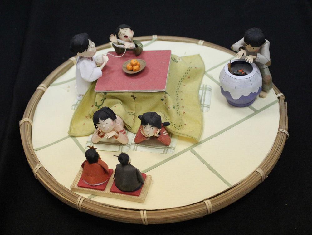 懐かしい冬の風景その２です　ペーパークラフト展でみつけたコタツの風景です　コタツでほぐした毛糸のセーターを巻き取る作業ですが子供の頃によくさせられたことを思い出します　今ではなくなった子どものお手伝い風景です