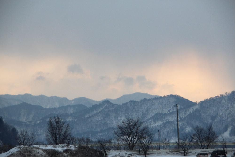 早春の山並みが朝焼けの染まっています　どことなく春を感じさせてくれる風景です　犬を連れて散歩している様子もどこか春の雰囲気を漂わせてくれています　今日も寒さは和らいだ天気のようです