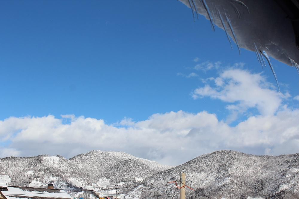 正月も明けました　今朝は積雪20センチほどありました　雪の予報ですが時折陽も射す穏やかな天気です　写真は昨日のものですが屋根のつららが少しずつ長くなり遠くの山は陽の光に輝いています　待ち焦がれるのは春です